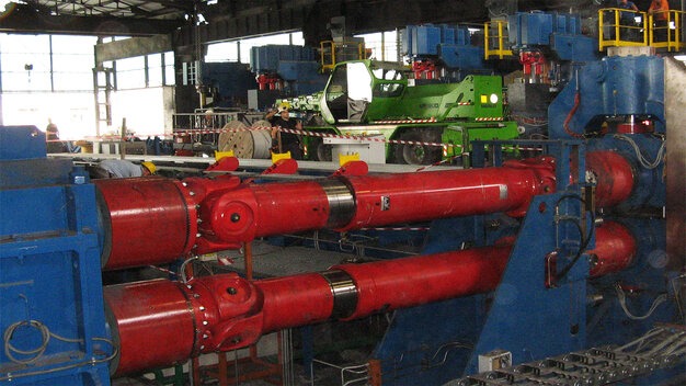 Industrial rolling mill with red shafts and crane